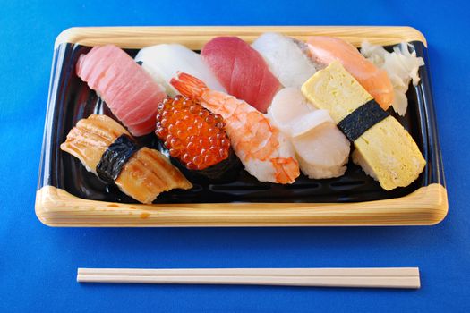 this is traditional Japanese Sushi set, seafood, raw fish and some kind of snack with rice bolls; macro-image sharp focus is on front food and chopsticks