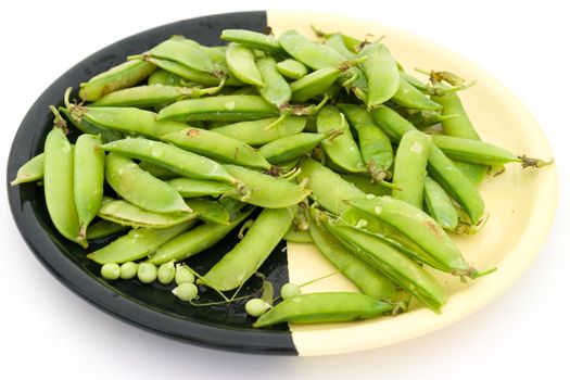 Peas pods on a plate on a white background