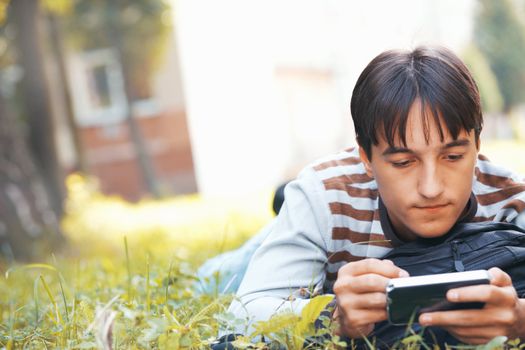 Young man with his pocket computer on a green grass