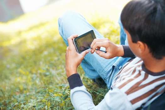 Young man with his pocket computer on a green grass