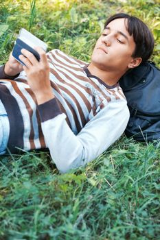 Young man with his pocket computer on a green grass