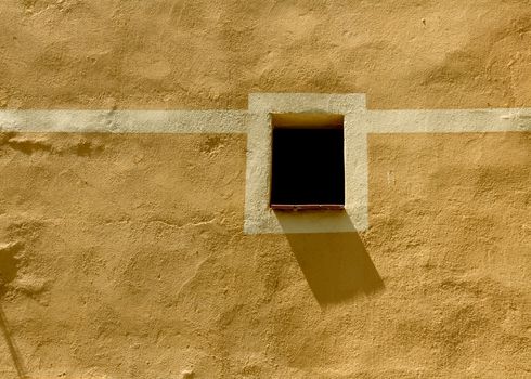 beautiful image of typical mediterranean scenery, little window and shadow on the facade on a sunny day