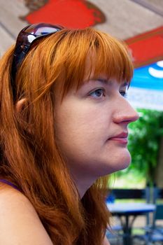 Portrait of the woman with red hair sitting on a summer verandah in cafe