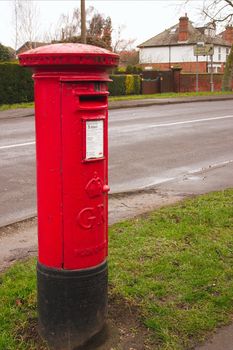 english red mailbox situated at the side of the road for public mail