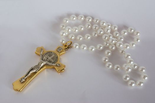 ornate crucifix with pearl bead rosary over a grey background