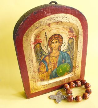 religious icon with a small rosary over yellow background