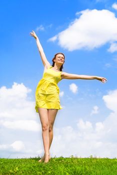 A beautiful girl on yellow dress and with red hair enjoying summer