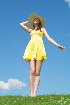 A beautiful girl on yellow dress and with red hair enjoying summer