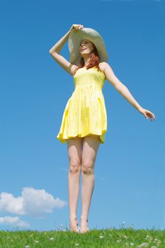 A beautiful girl on yellow dress and with red hair enjoying summer