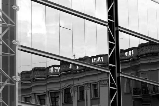 Old house reflected in modern building windows black and white