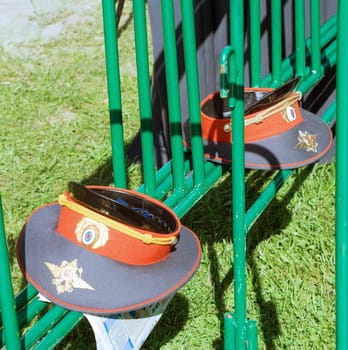 Two Russian police service caps on a green metal fence