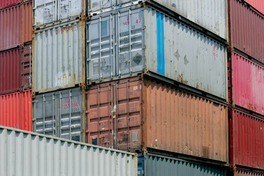 Shipping containers waiting to be loaded on a cargo ship.  Numbers and markings have been altered to have no meaning or reference.
