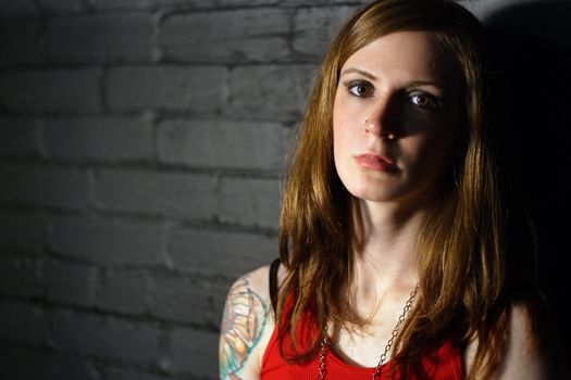 Image of a serious girl with upper arm tattoo.  Harsh lighting for more dramatic effect.
