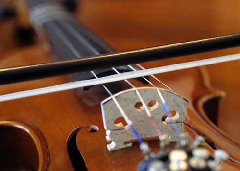 Closeup of a bow on the strings of a violin.
