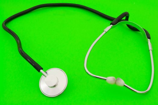 Small medical stethoscope on a green background