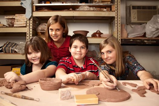 Four children posing for portrait in a clay studio