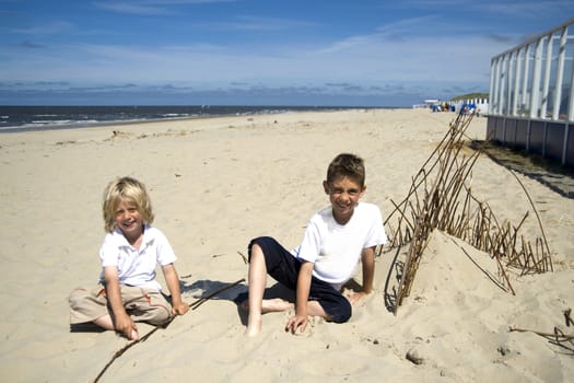 two boys playing with boughs on the beach in Texel