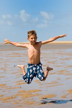 a boy jumping high on the beach