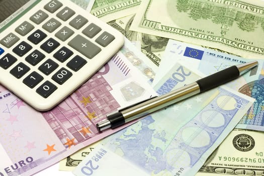 Dollar, euro banknotes, calculator and pen