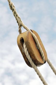 Wooden block with ropes against the sky