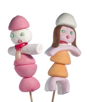 A male and a female figurine made out of candies on a stick over a white background.