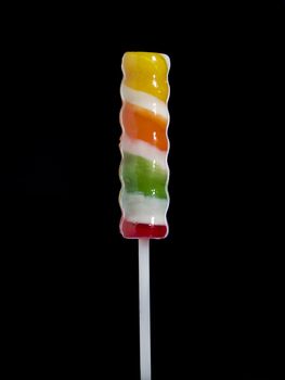 A stick lollipop isolated over black background.