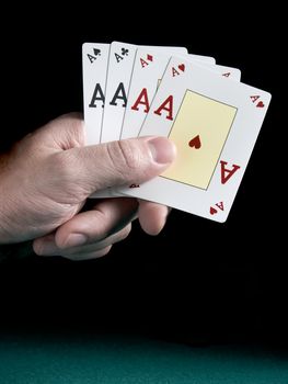 A man's hand holding four aces isolated on black background.