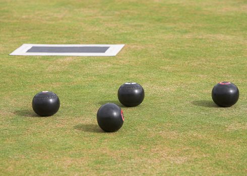 Game of lawn bowls with bowling woods and mat.