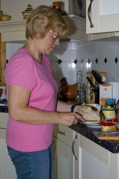 elderly woman is making sandwiches in the kitchen