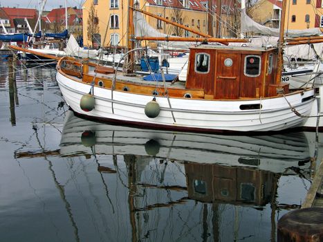 Traditional wooden sailboat reflected in the water in Svendborg Marina Denmark