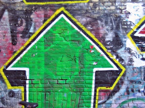 Graffiti of a green arrow on bricks wall