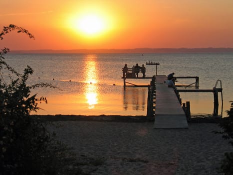 Sunset time of a dock with seated people in Langeland Denmark