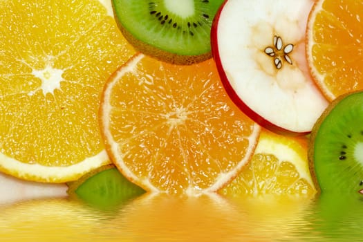 fruits background from slices kiwi, apple, tangerine and orange in water