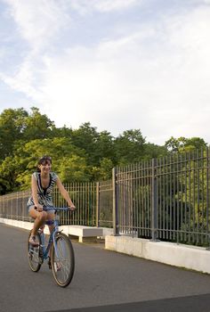 A young woman riding her bicycle across the bridge.