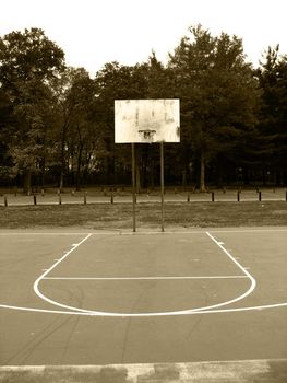 A basketball hoop found at the park in sepia tone.