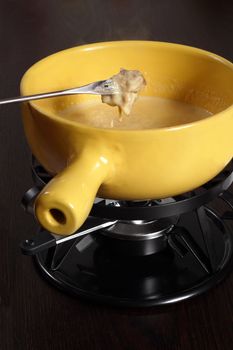 Bread being dipped into the melted cheese in the fondue bowl.
