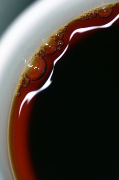 Extreme close-up of coffee with beautiful highlights and bubbles- could also be used as an image of tea