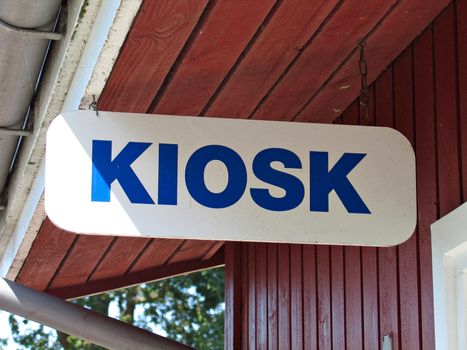 Sign of a kiosk hanged with metal wires from a wooden roof