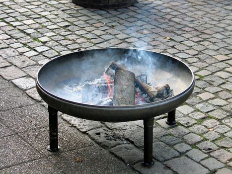 Fire pit in classical design made from copper with burning logs