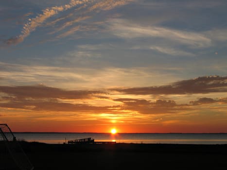 Dramatic sunset into the ocean over an old wooden dock