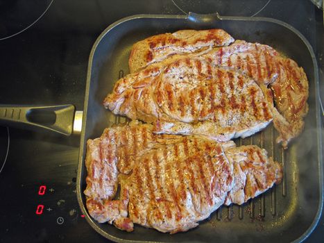 Steaks being made on a cast iron frying pan