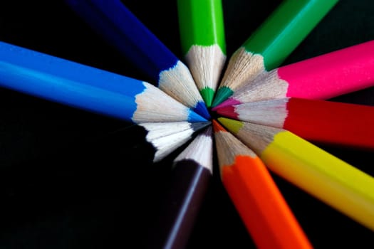 ring of assorted coloured crayons against a dark background