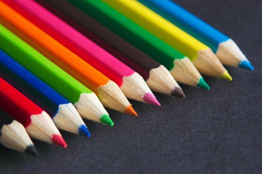 row of coloured pencil crayon points against  a dark background