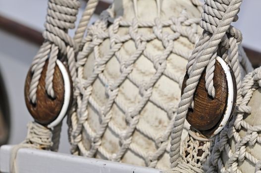 Close-up of old blocks on an sailboat with bumpers covered of rope net