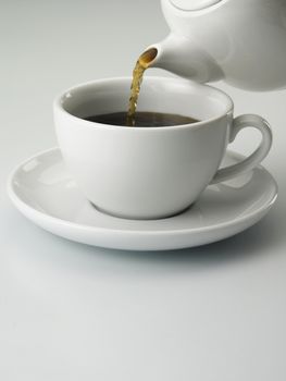 close up of a cup with tea and tea pot