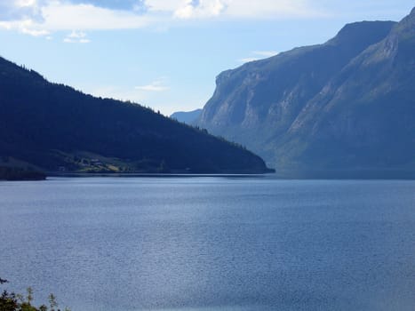 High green mountains meet clear deep blue water in of of Norway's fjords