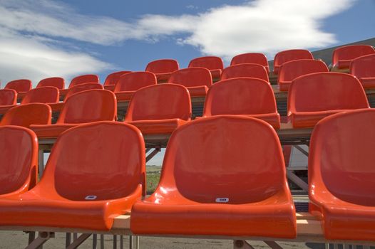 Red seats on a background of the sky with clouds.