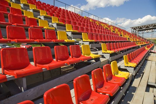 Red and yellow seats on a background of the sky with clouds.
