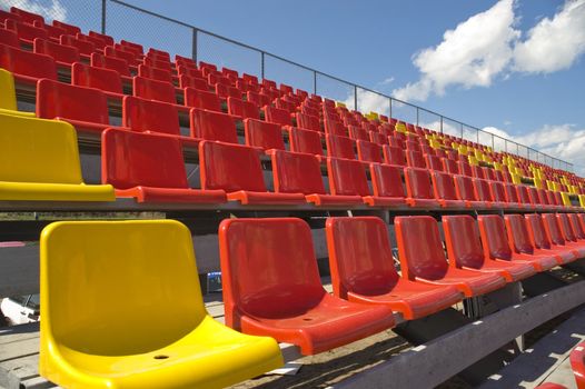 Red and yellow seats on a background of the sky with clouds.