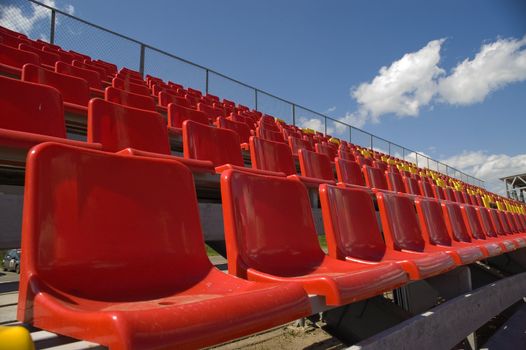 Red seats on a background of the sky with clouds.